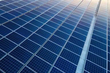 Blue photovoltaic solar panels mounted on building roof for producing clean ecological electricity at sunset. Production of renewable energy concept.